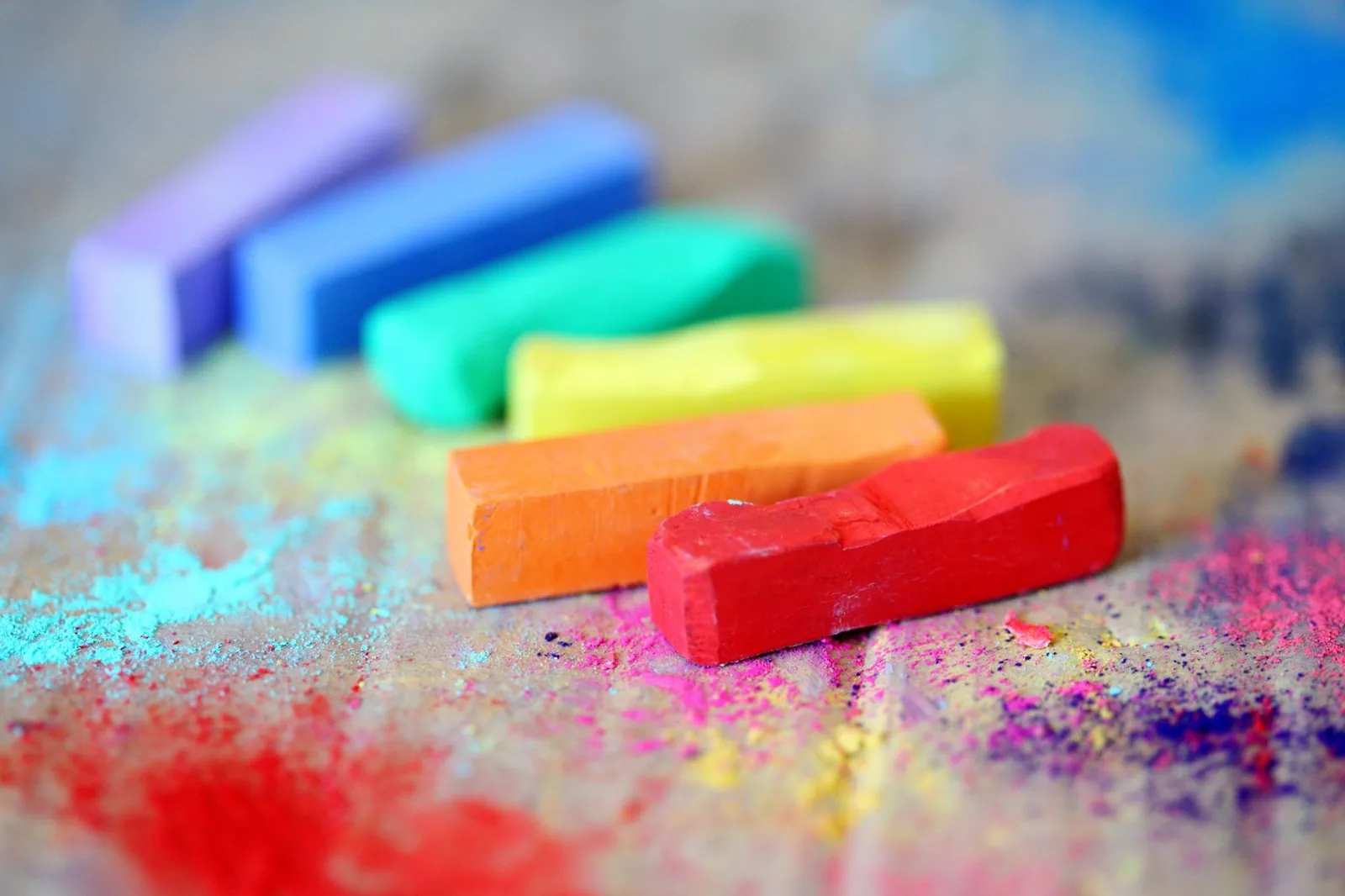 Rows of assorted colored chalk sticks on a wood surface, showing how different hues carry different moods — the color principle in visual design